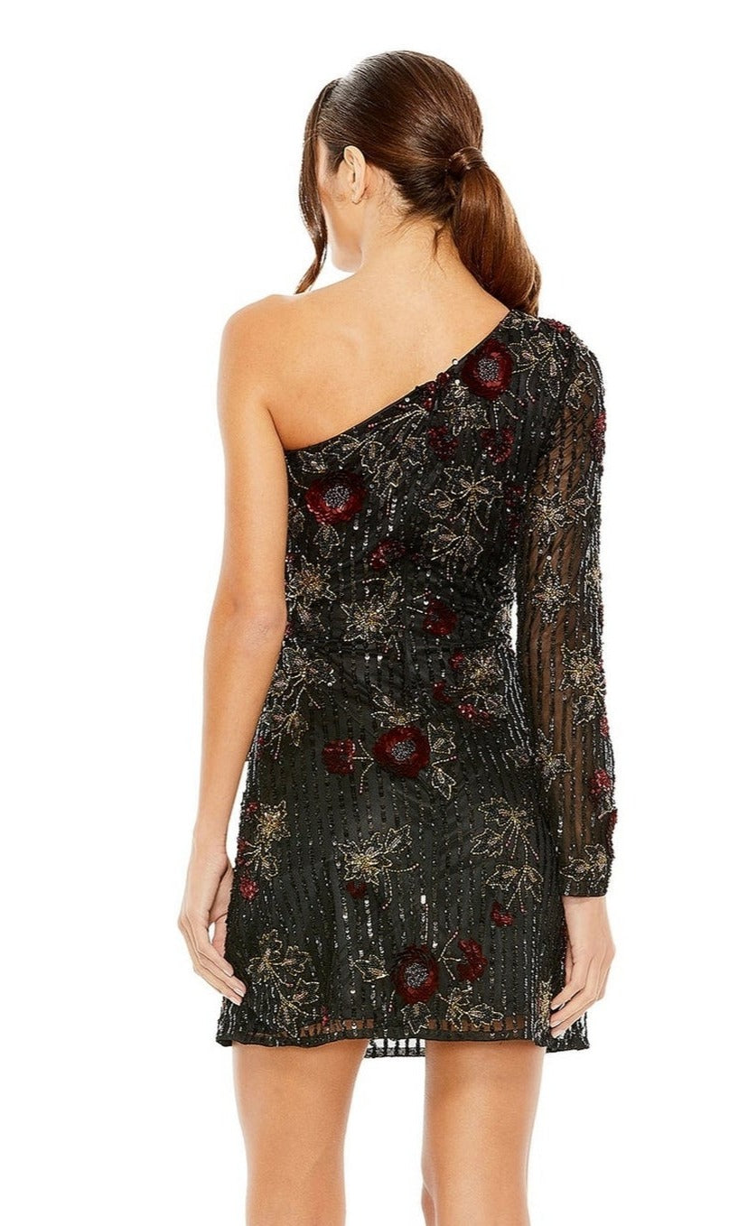 A woman with brown hair in a low ponytail is shown from the back wearing the Short Homecoming Dress 5919 by Mac Duggal— a black, beaded fitted dress featuring sheer floral details and a one-shoulder design.